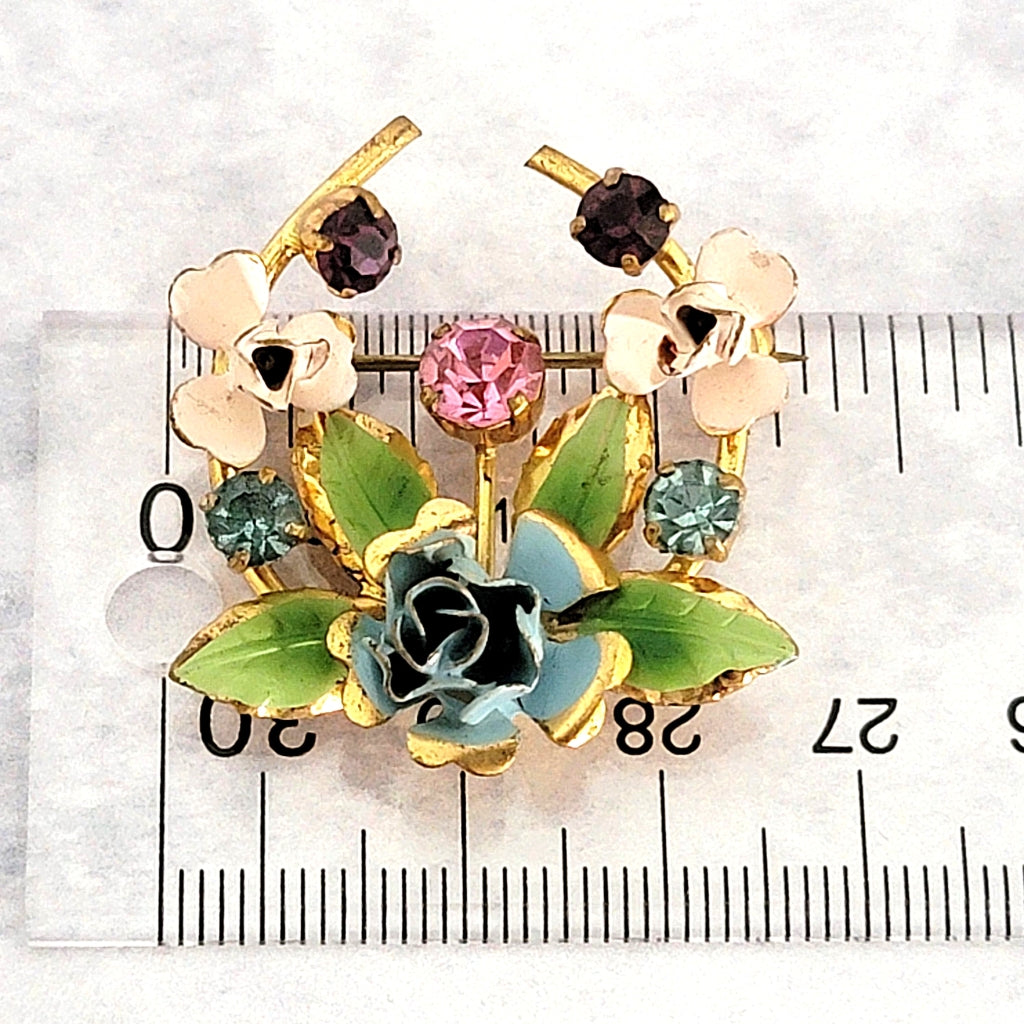 Vintage floral brooch sitting on a ruler.