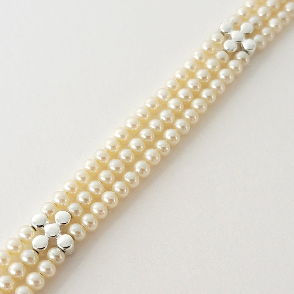 Back of a faux pearl three strand necklace.