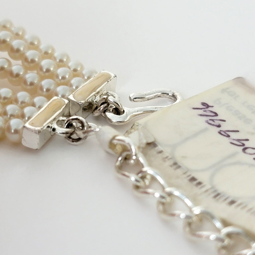 Clasp and paper tag on a necklace.