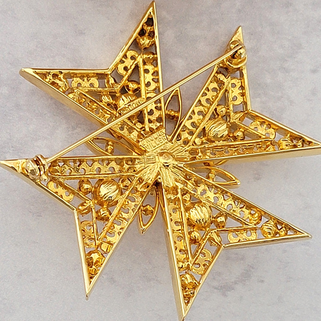 Back of a gold tone brooch.