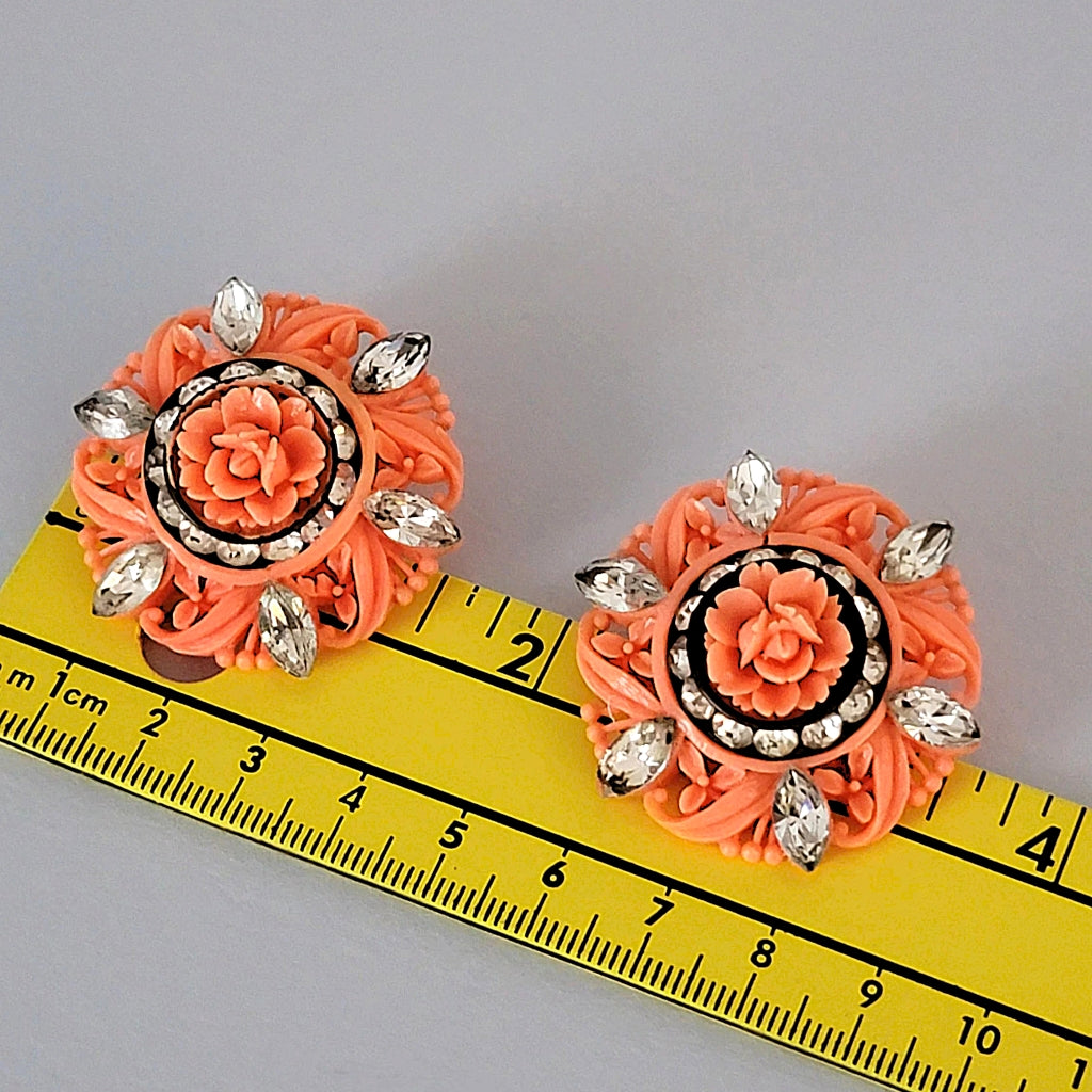 Vintage plastic flower earrings next to a ruler.