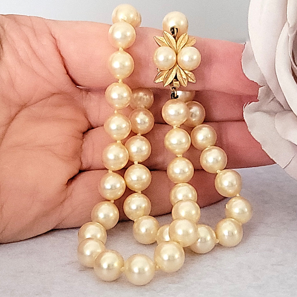 Vintage faux pearl choker in hand.