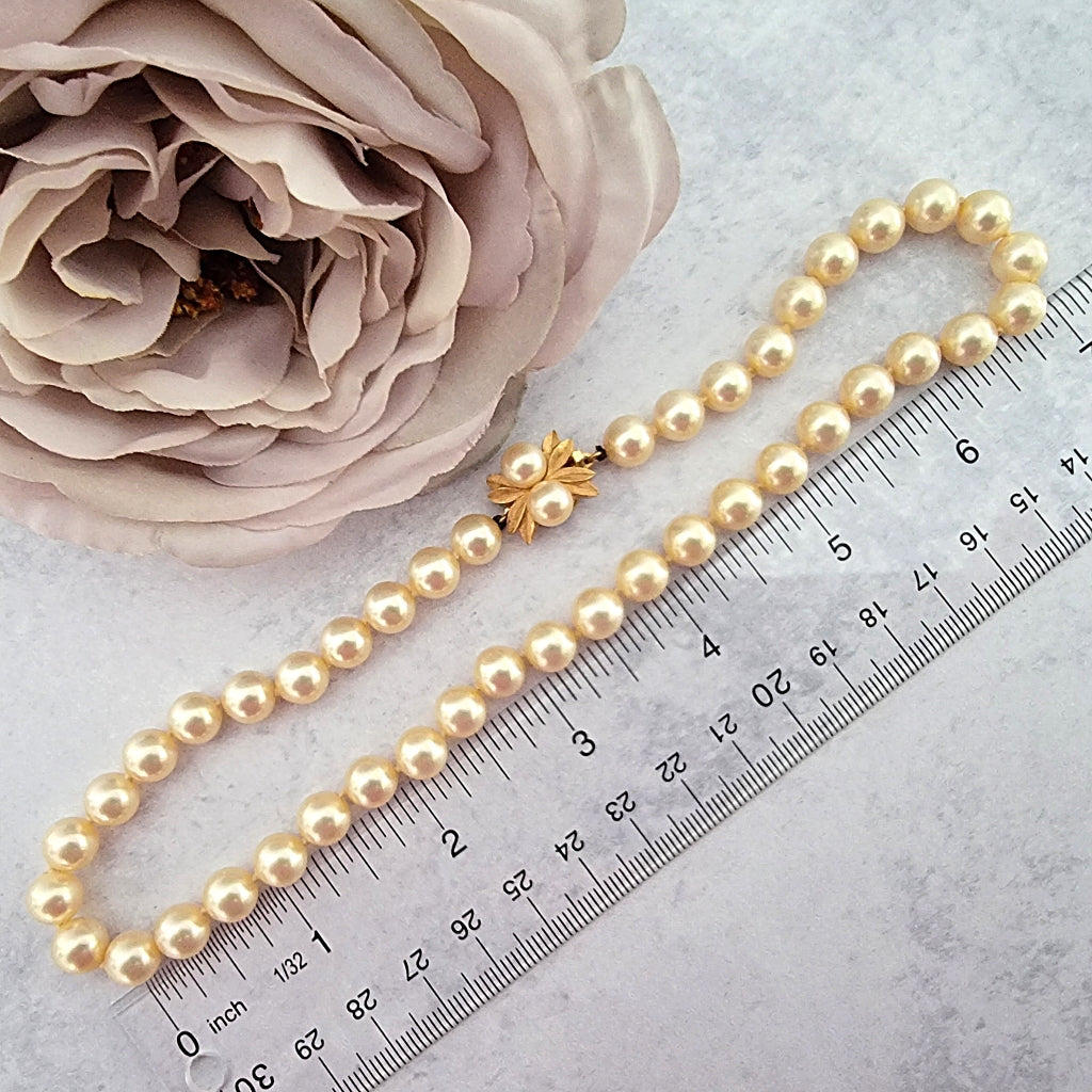60s style faux pearl choker next to a ruler.