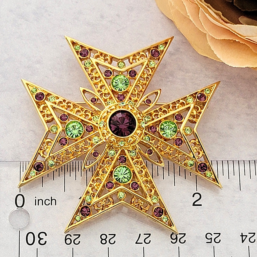 Rhinestone cross pin next to a ruler.
