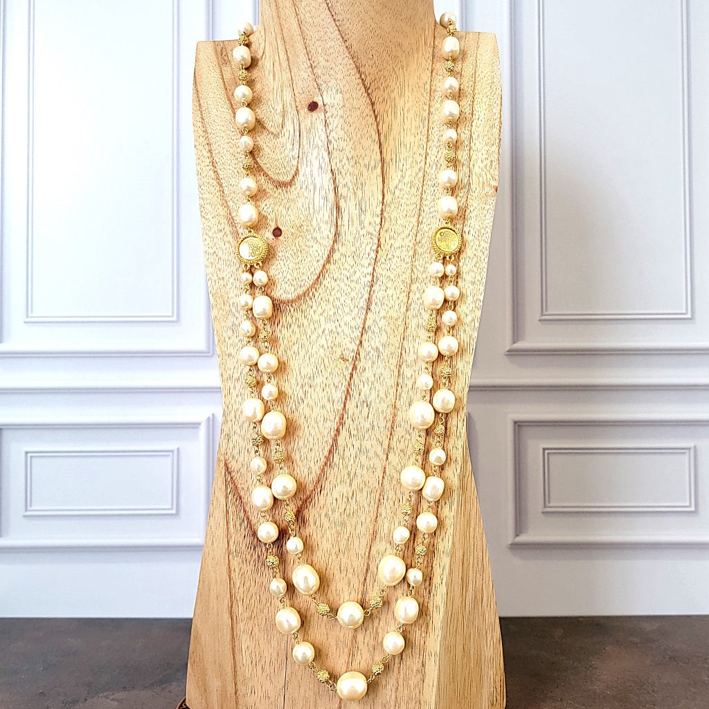 Long faux pearl necklace on a wooden display stand.