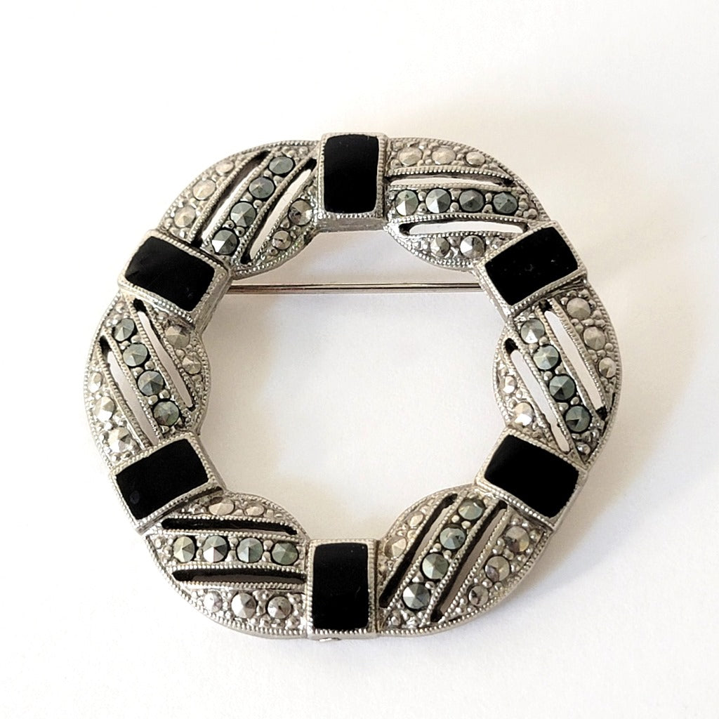 Silver tone brooch with black enamel and marcasite rhinestones.