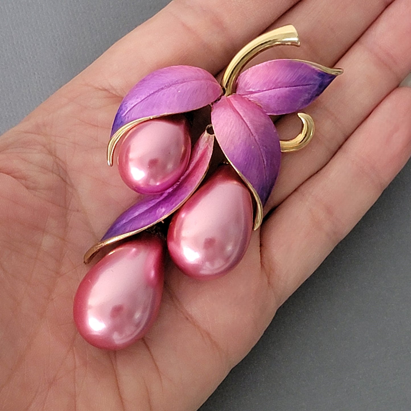 Large pink and purple faux pearl brooch in hand.