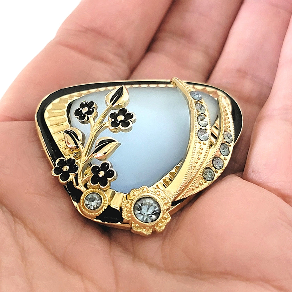 Vintage blue glass and rhinestone pin in hand.