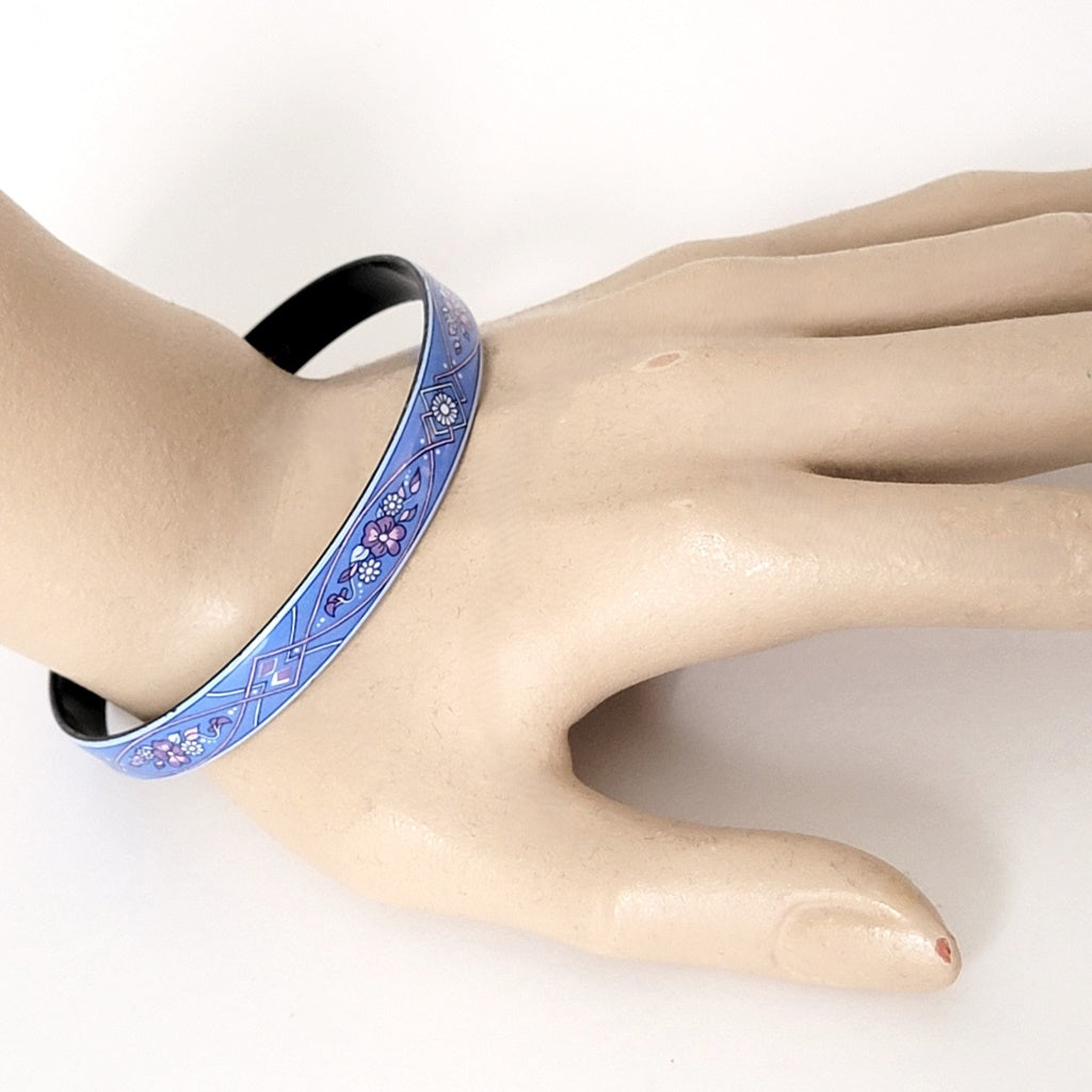 Blue enamel flower bracelet on wrist.