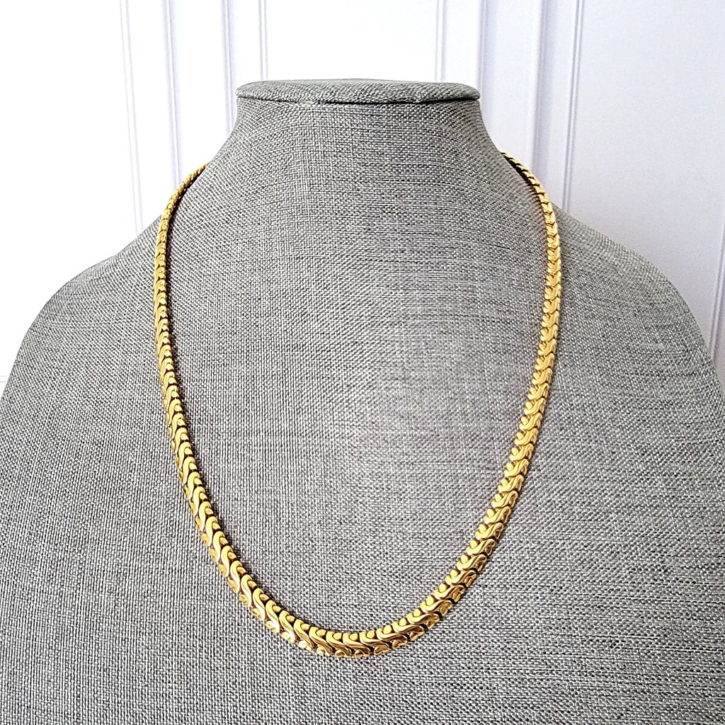 Wide gold tone chain on display stand.