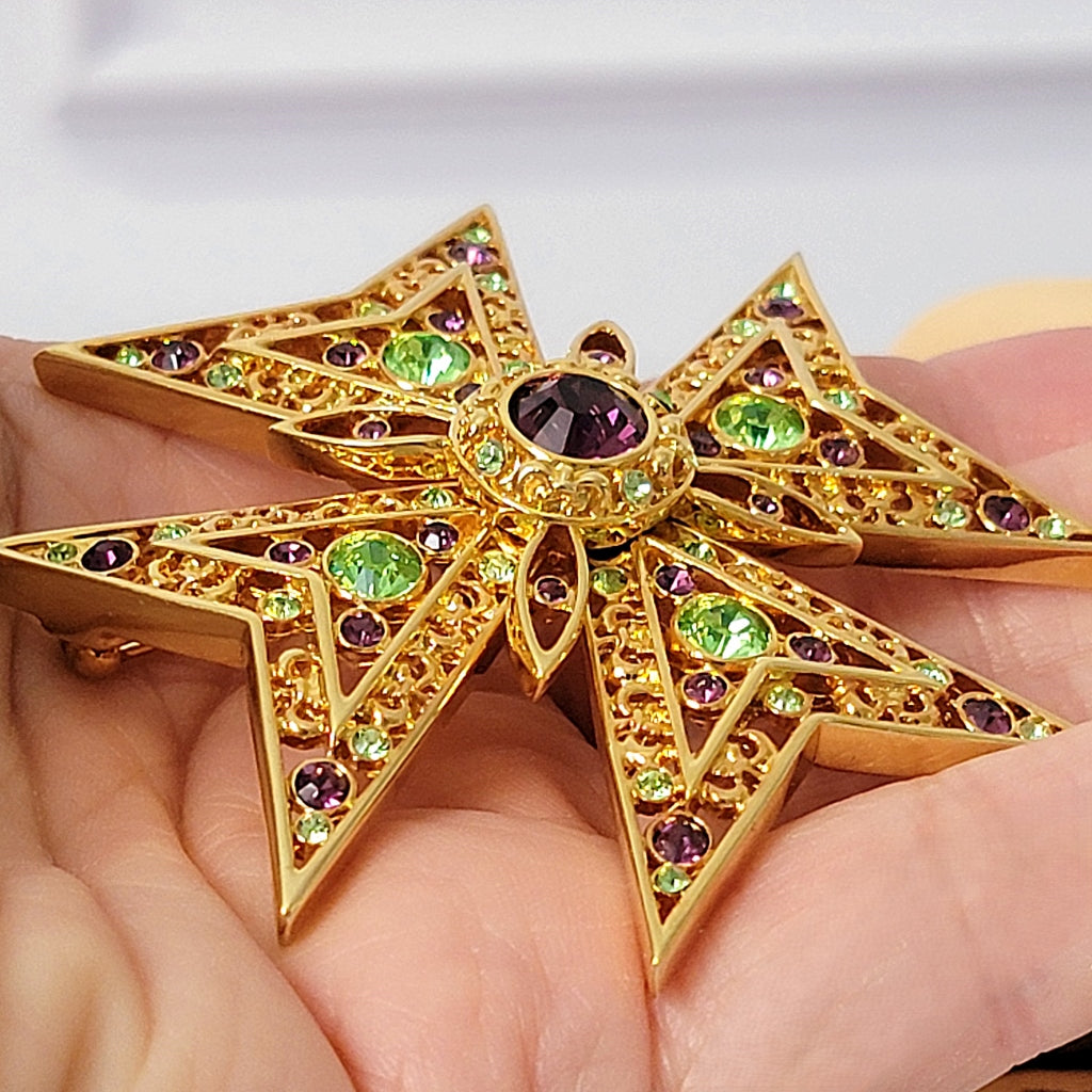 Crystal rhinestone cross pin in hand.