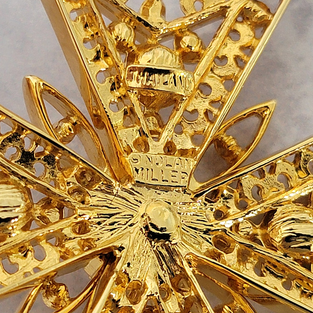 Nolan Miller signature mark on the back of a brooch.