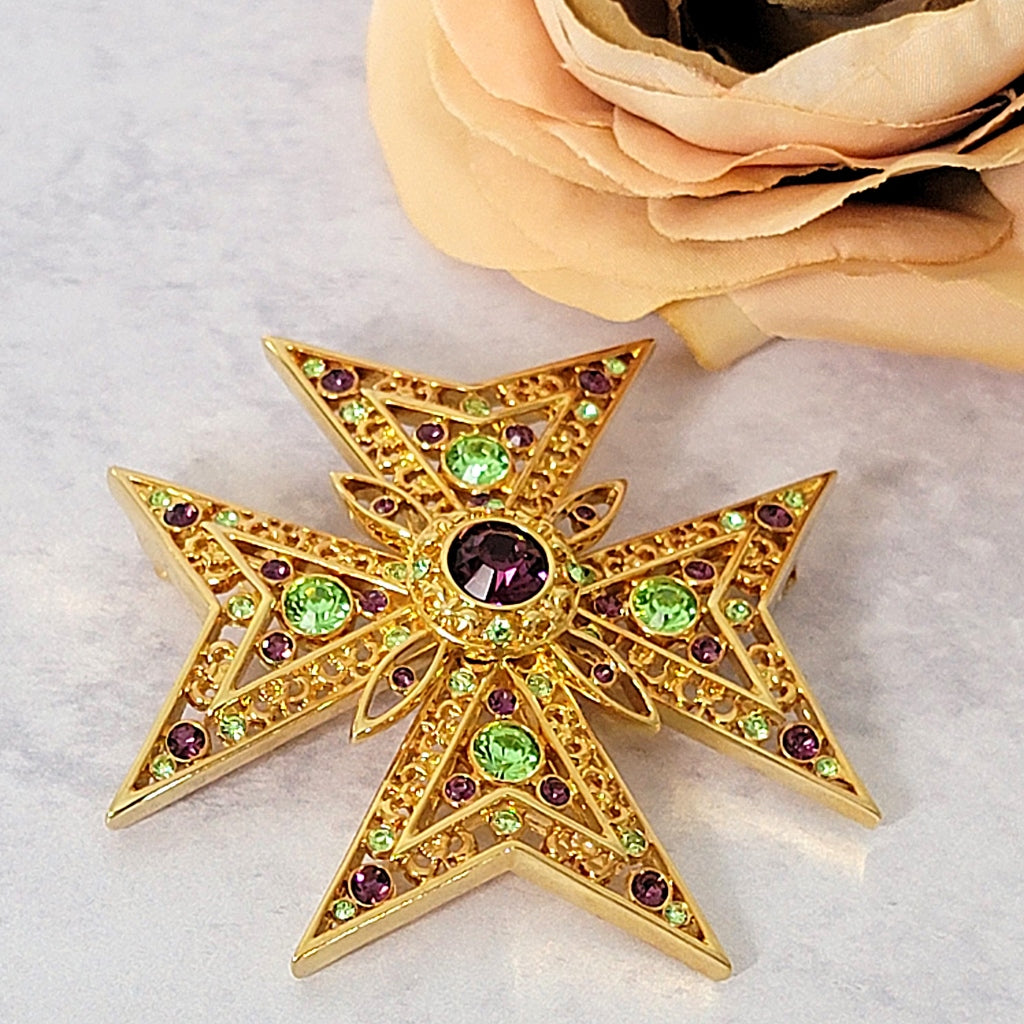 Maltese cross brooch next to a flower.