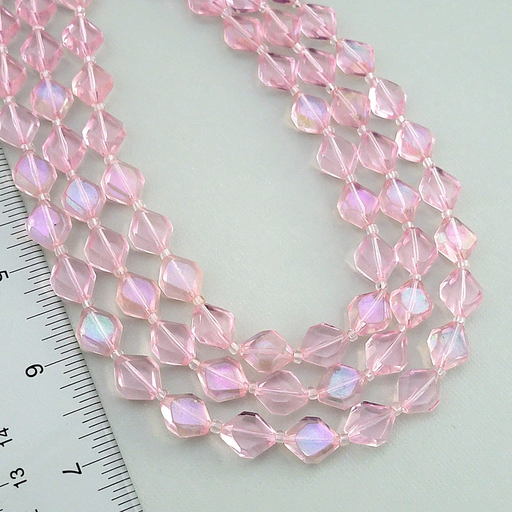 Pink translucent plastic beads next to a ruler.