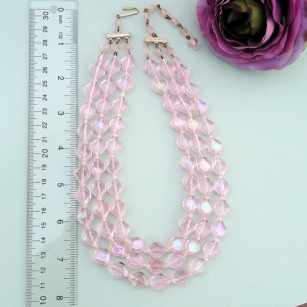 Vintage pink lucite necklace next to a ruler.