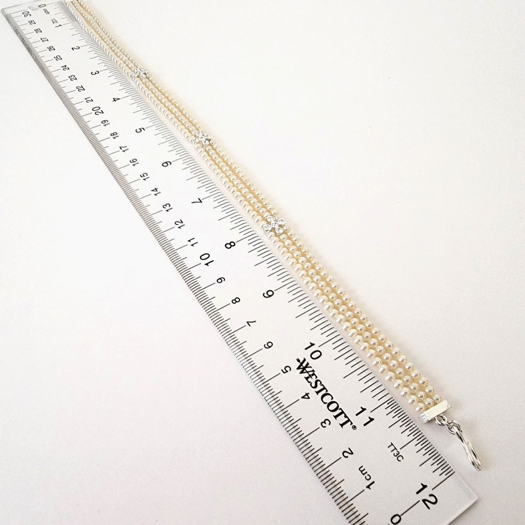 Faux pearl choker next to a ruler.