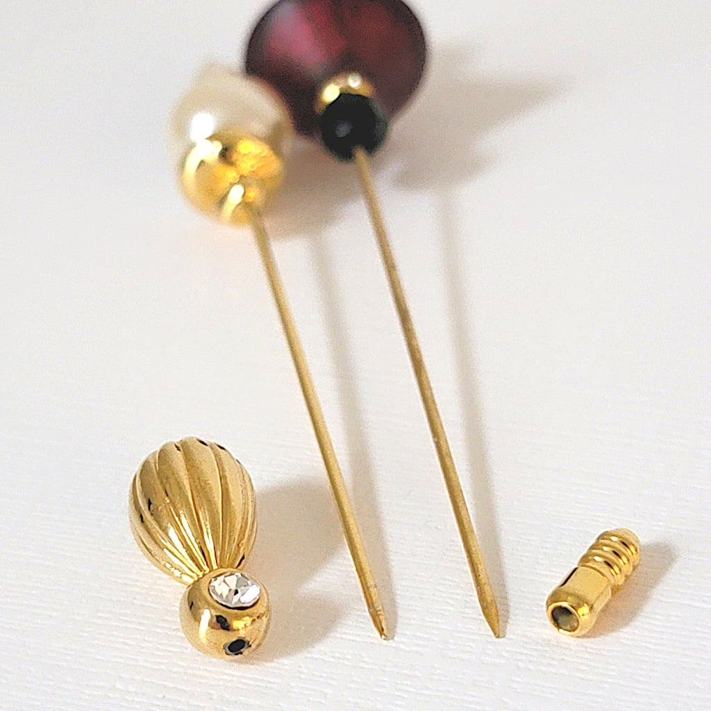 Pointed ends of two stick pins with clutches detached.