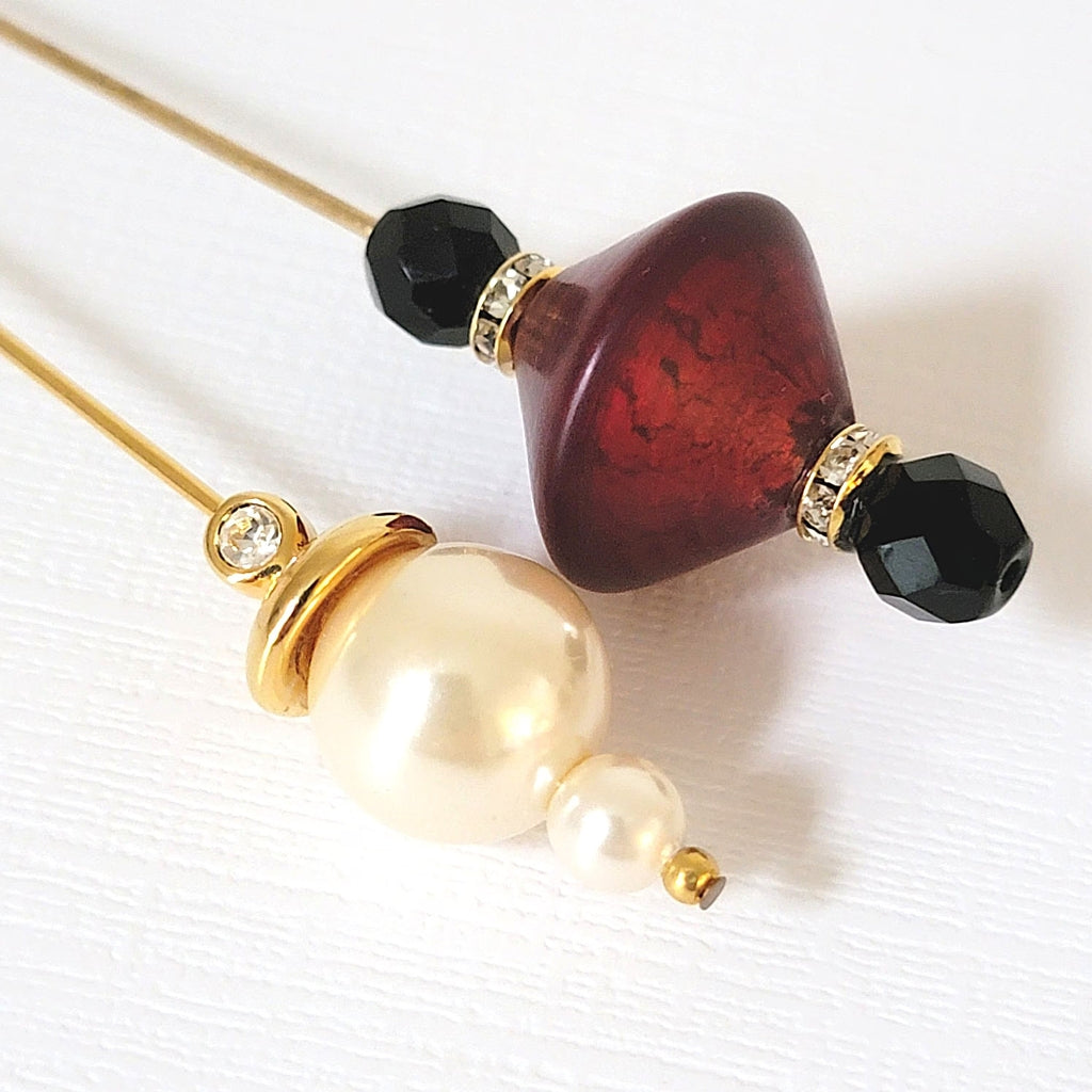 Tops of two stick pins with red and black glass, faux pearls and rhinestones.