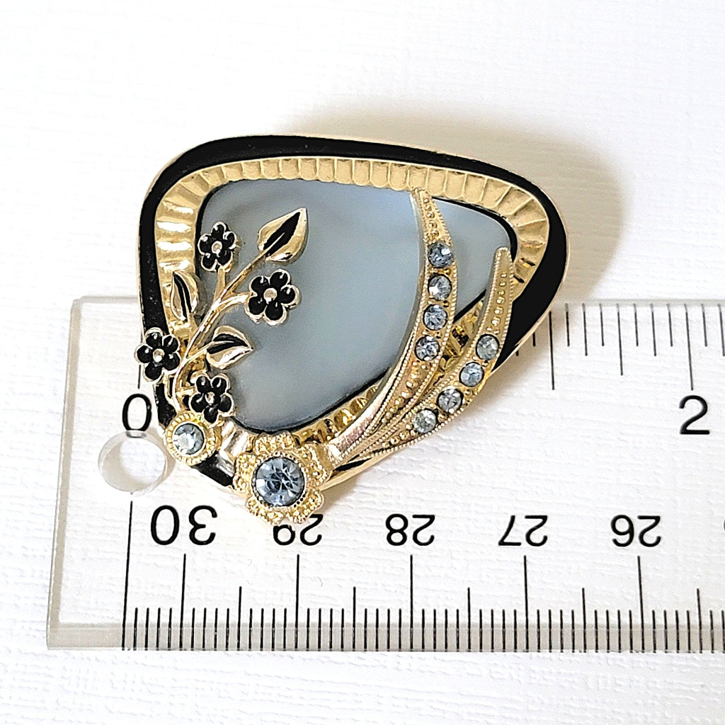 Blue floral pin next to a ruler.