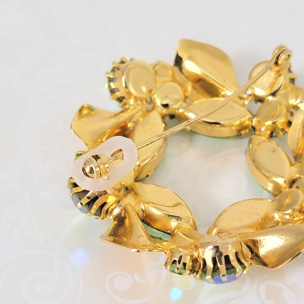 Back view of green rhinestone wreath pin, showing clasp and silcone lock.
