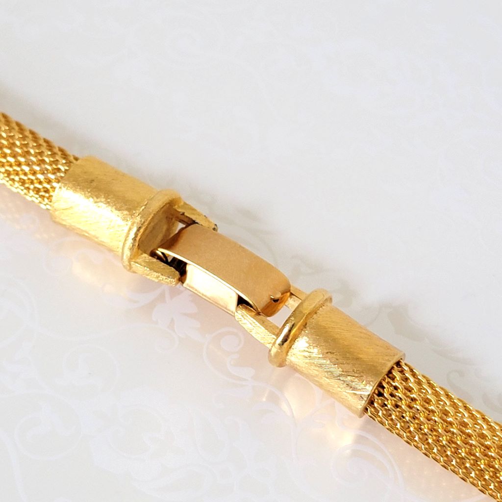 Closeup view of an closed, gold tone, Anne Klein mesh necklace clasp.