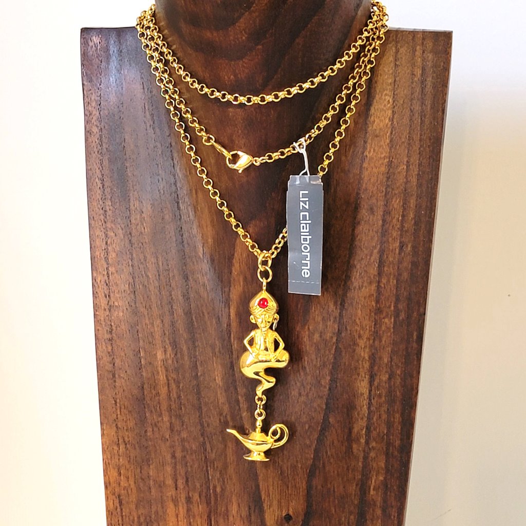 Liz Claiborne long gold tone chain necklace, with genie pendant and bottle charm. Shown on a display stand, with paper hang tag.