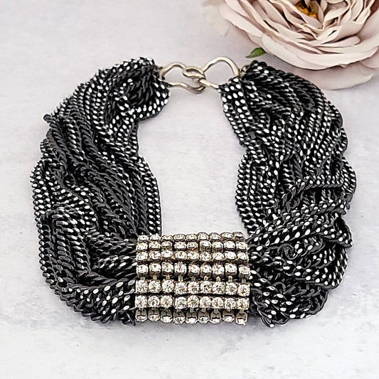 Chunky multi strand choker necklace with a rhinestone center.
