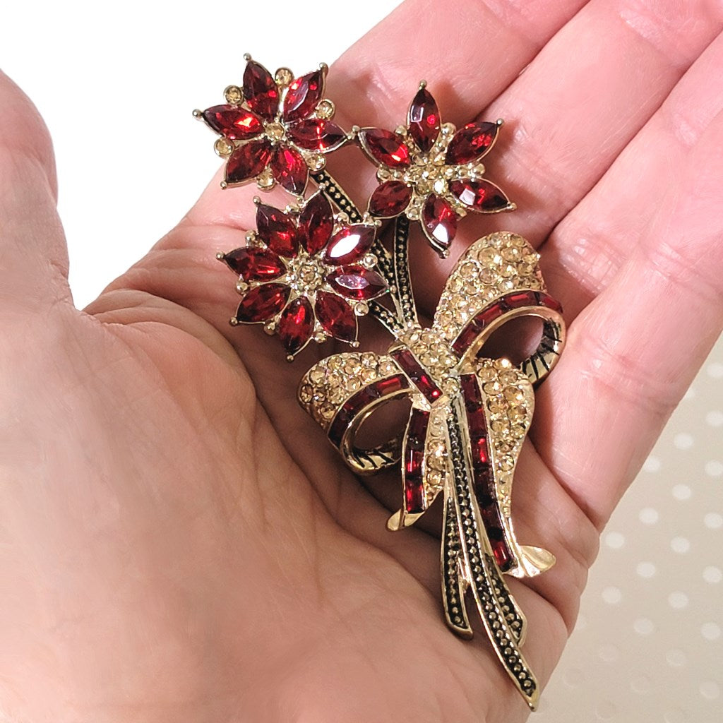 Avon red and gold rhinestone, poinsettia brooch, shown in hand, for size comparison.