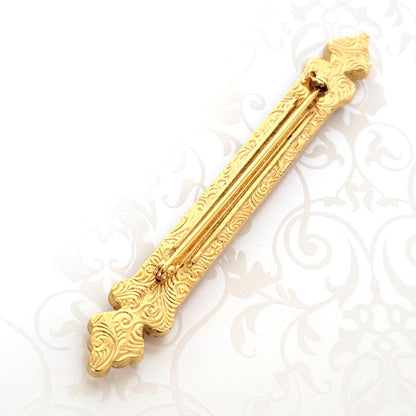 Back view of a vintage 1928 bar brooch, showing the gold tone and signature swirl pattern.
