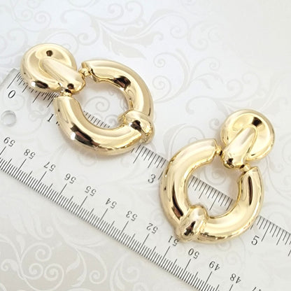 Gold tone hoop clip on earrings, next to a ruler.