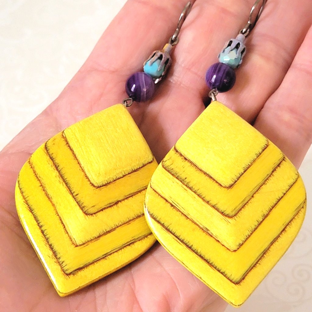 Handcrafted large yellow wood dangle earrings, shown in hand, for size comparison.