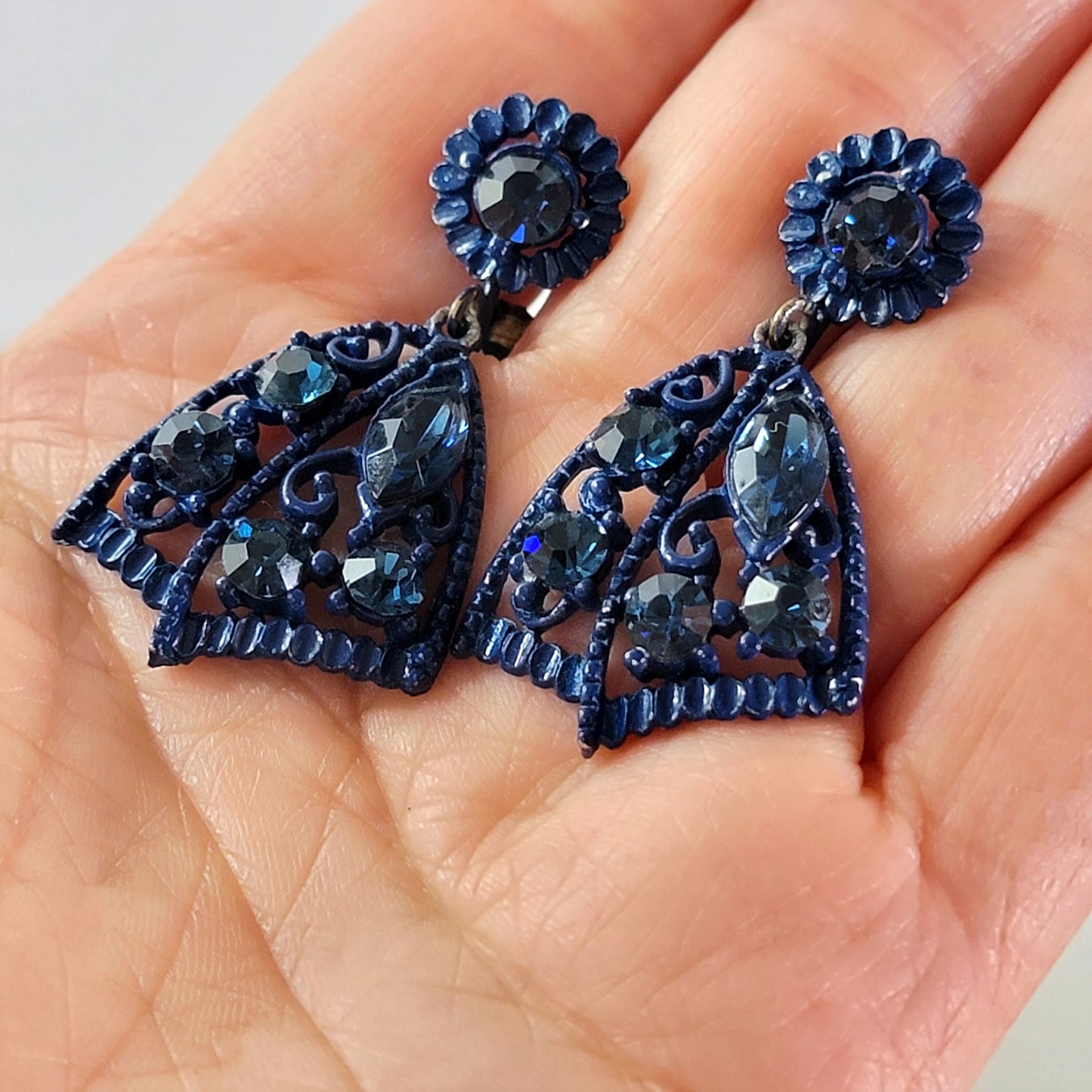Blue rhinestone dangle earrings in hand.
