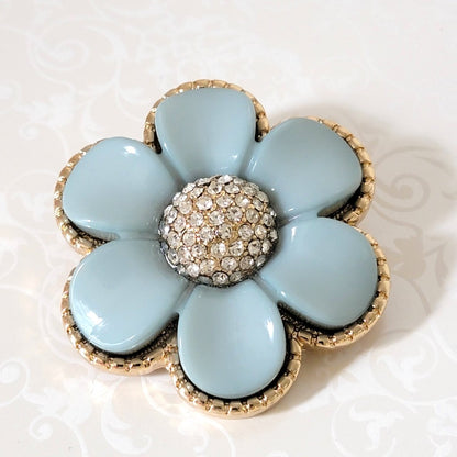 Light blue vintage style acrylic flower brooch, with glass rhinestones and a gold tone edge setting.