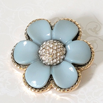 Sky blue thermoset style plastic flower pin, with pave rhinestone center and gold tone edges.