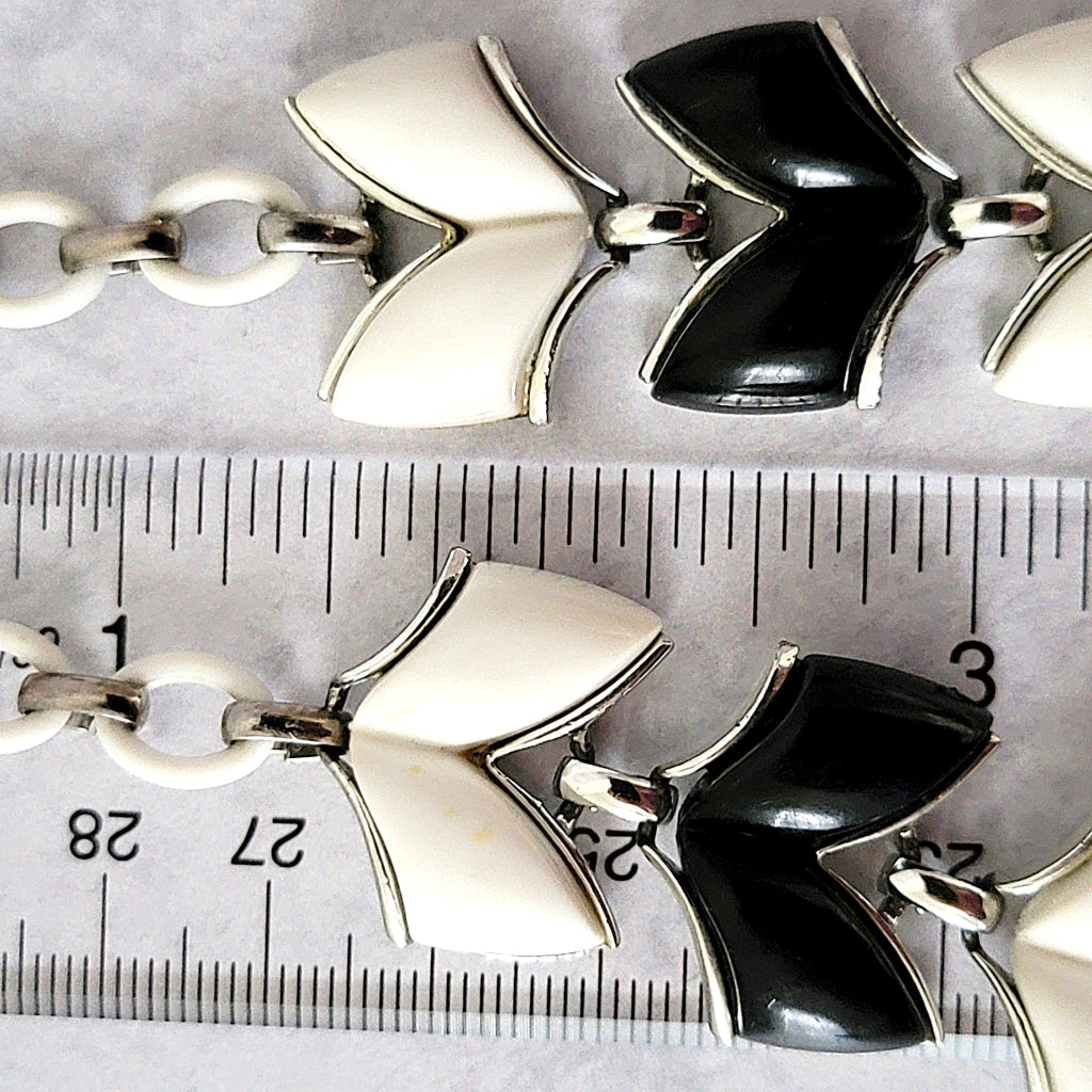 Plastic chevron shaped necklace links next to a ruler.