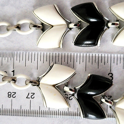 Plastic chevron shaped necklace links next to a ruler.