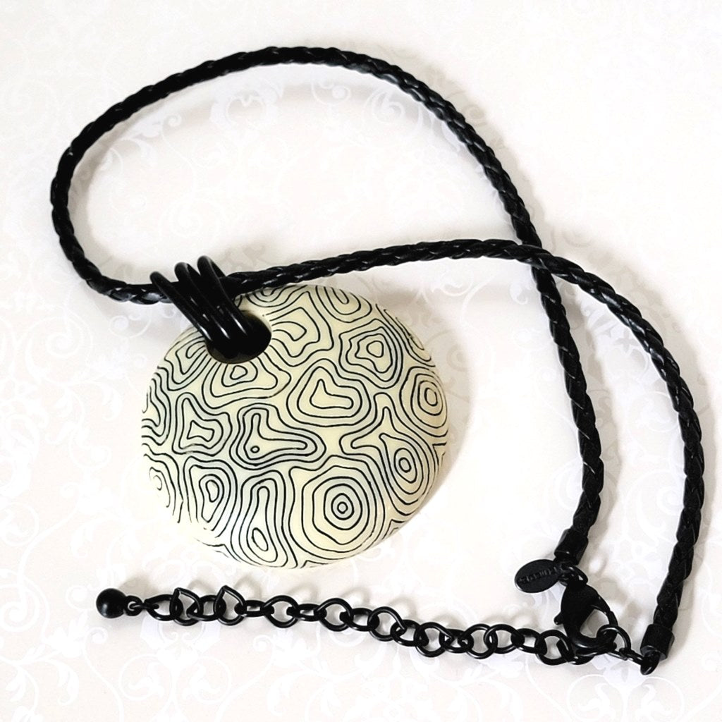 Chicos, abstract swirl pendant necklace. Giant circle, on a black braided leather look cord, with extender chain.