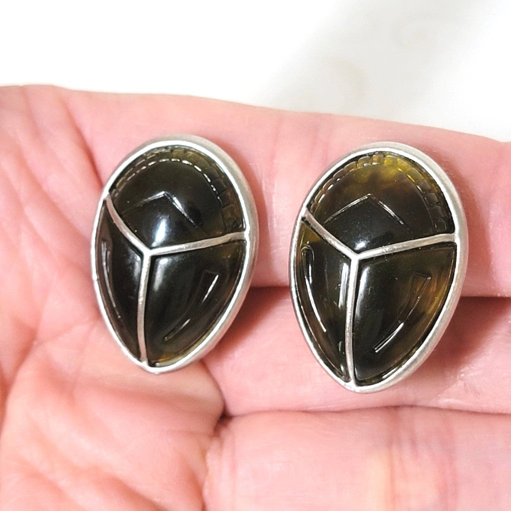 Claiborne beetle clip on earrings, shown in hand, for size comparison.