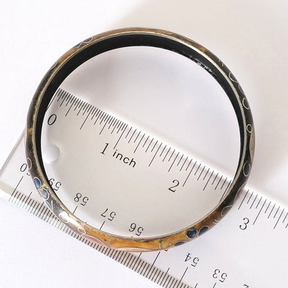 Cloisonne bracelet next to a ruler.