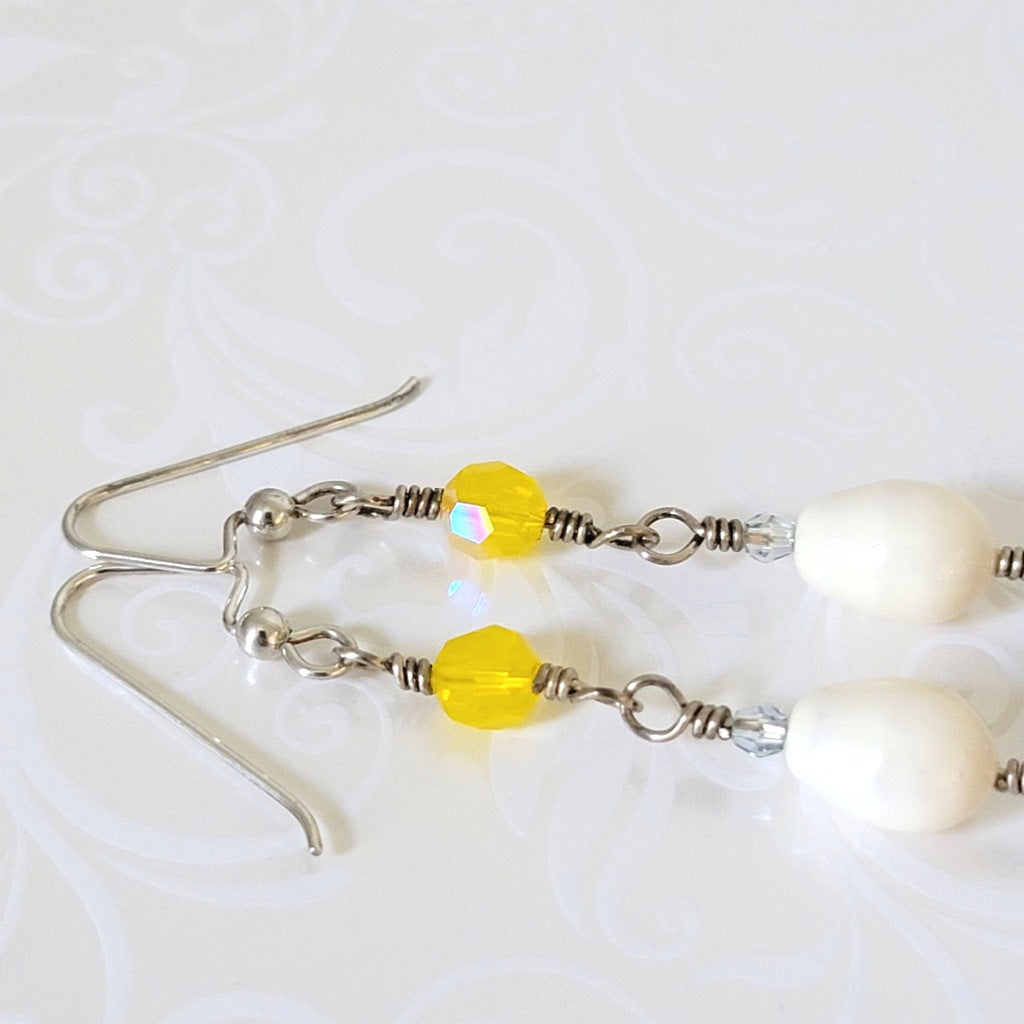 Close-up view of yellow crystals on silver earrings.