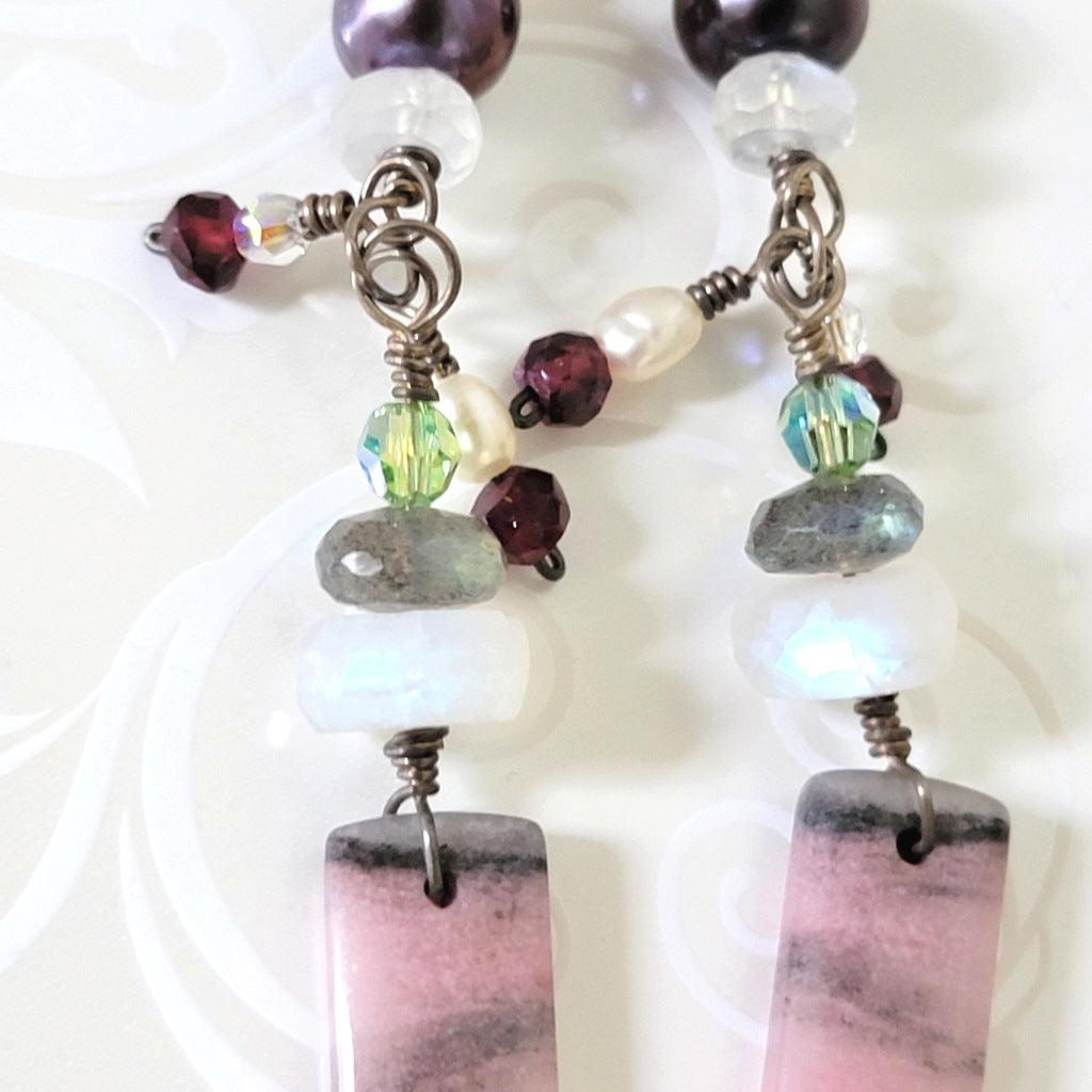 Close-up view of gemstone earrings, with pearls and moonstones.