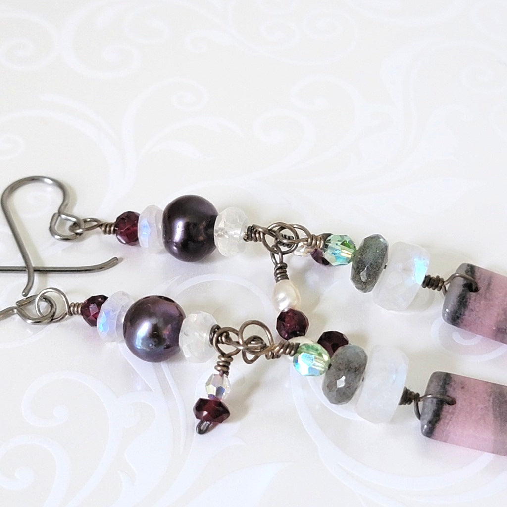 Close-up view of gemstone earrings, with pearls, moonstone, and labradorite.