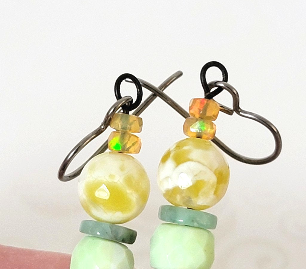 Close-up view of tiny opal beads, atop a pair of gemstone flower dangle earrings.