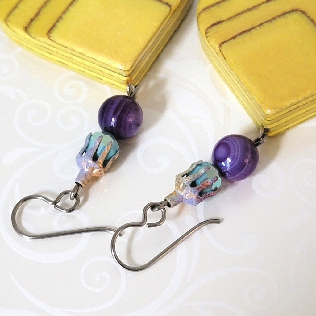 Close-up view of purple agate, turquoise glass, enamel spatter bead caps, and niobium ear wires.