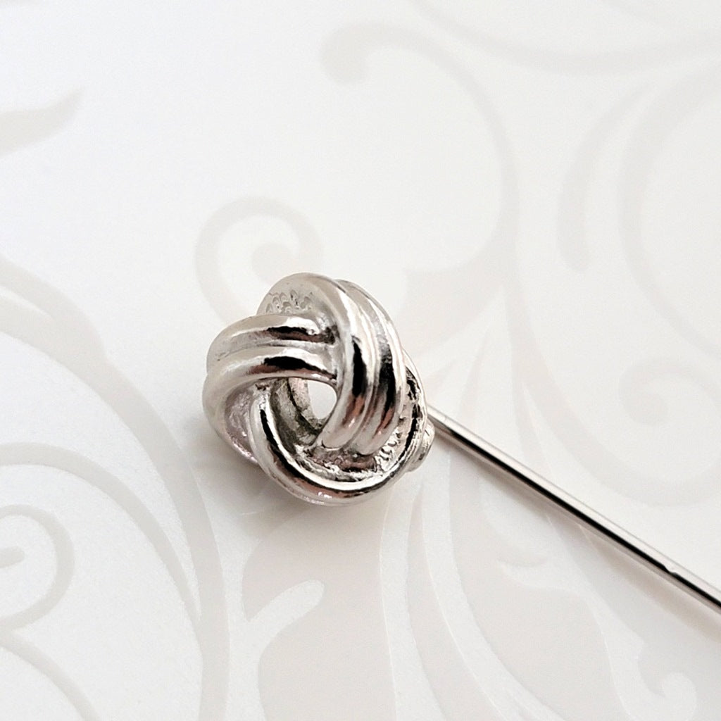 Close-up view of a Monet silver tone knot stick pin head.