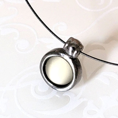 Closeup view of a glass glow pendant on a vintage choker by Express.