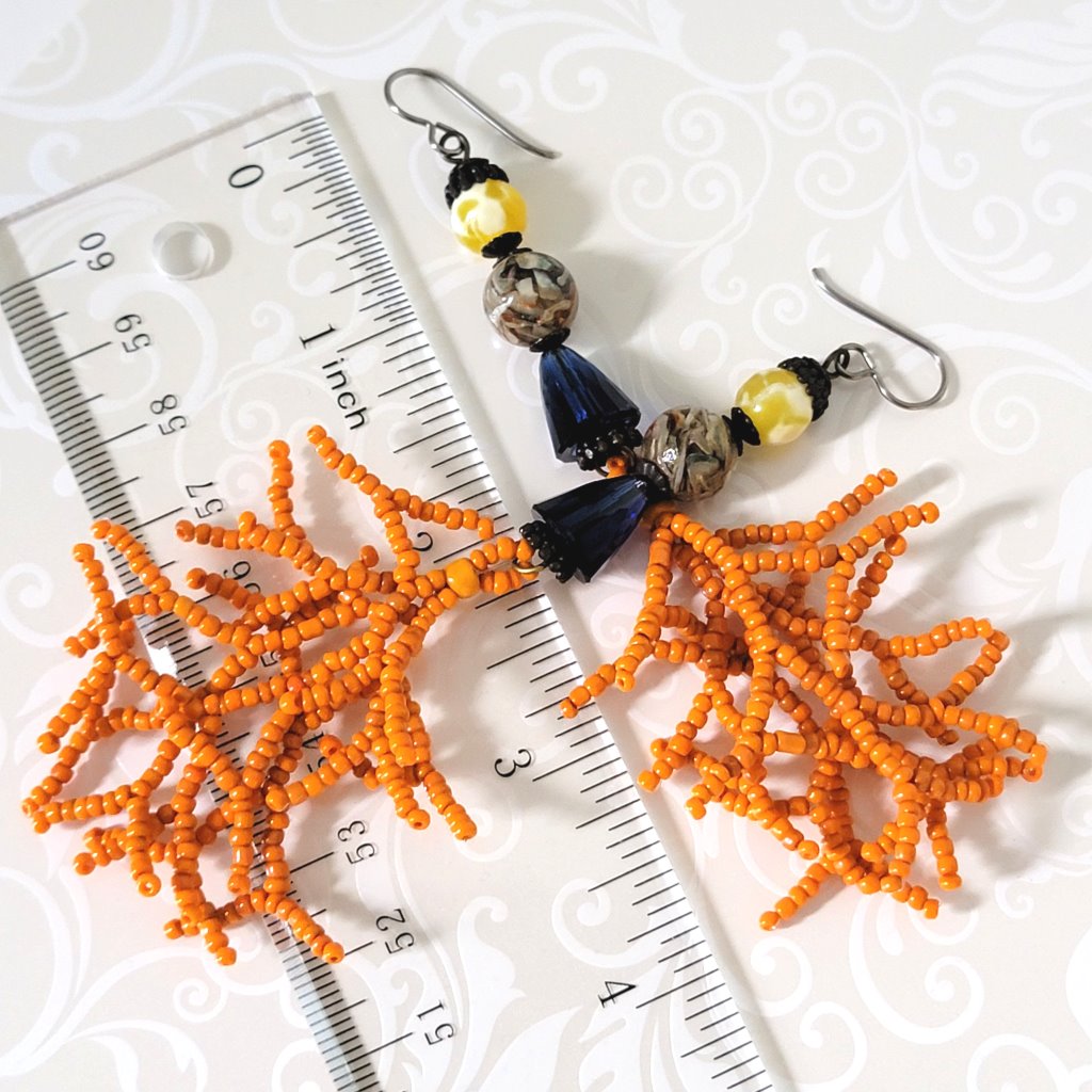 Long dangle earrings, with orange seed bead branches. Shown next to a ruler.
