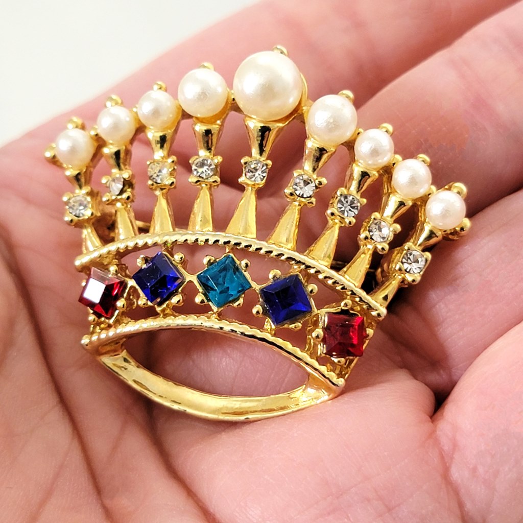 Faux pearl crown brooch in hand.