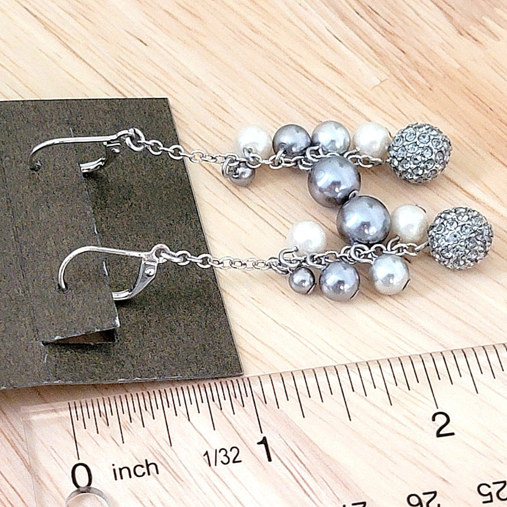 Long faux pearl dangle earrings next to a ruler.