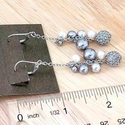 Long faux pearl dangle earrings next to a ruler.